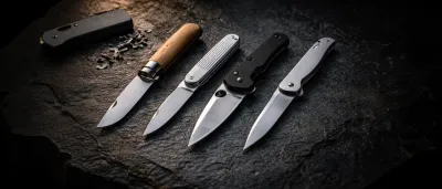 Vier Taschenmesser nebeneinander auf dunklem Untergrund